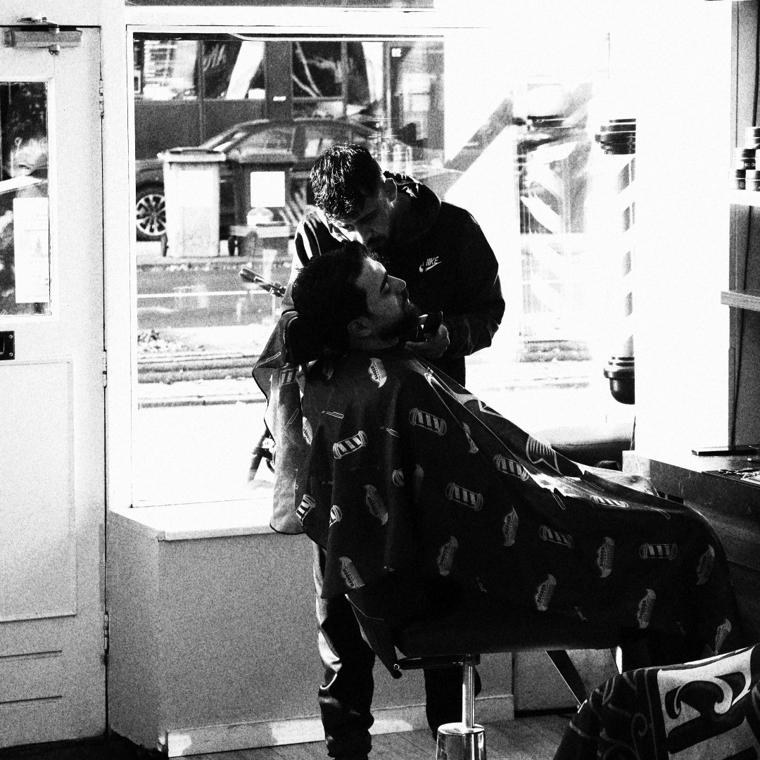 Zwart-witfoto van een barbier aan het werk bij Mo’s Barbershop